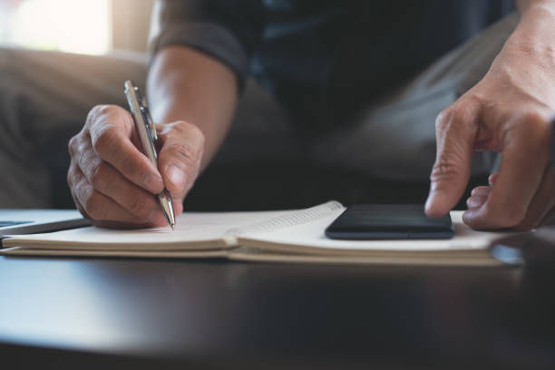istock Man hand with a pen writing on paper notebook 1395859471