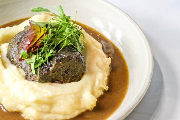 istock Braised ox cheeks on celery potato puree with brown sauce and wild herb garnish in a deep plate, selected focus 1395861176
