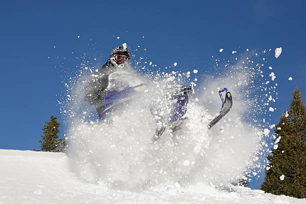 Extreme snowmobiling in bank of snow snowmobile rider exploding though fresh powder Snowmobiling stock pictures, royalty-free photos & images