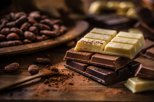 Stack of dark, milk and white chocolate bars with cocoa beans