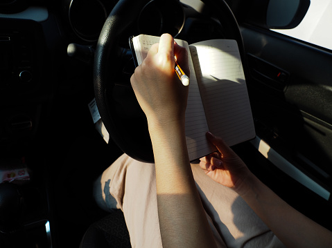 A woman who is taking notes in the car's notebook
