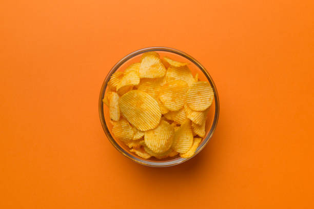 istock Potato chips on bowl isolated on colored background. Delicious crispy potato chips in bowl. Space for text. Top view 1395865491