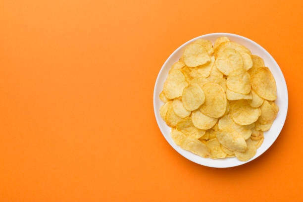 istock Potato chips on bowl isolated on colored background. Delicious crispy potato chips in bowl. Space for text. Top view 1395865515