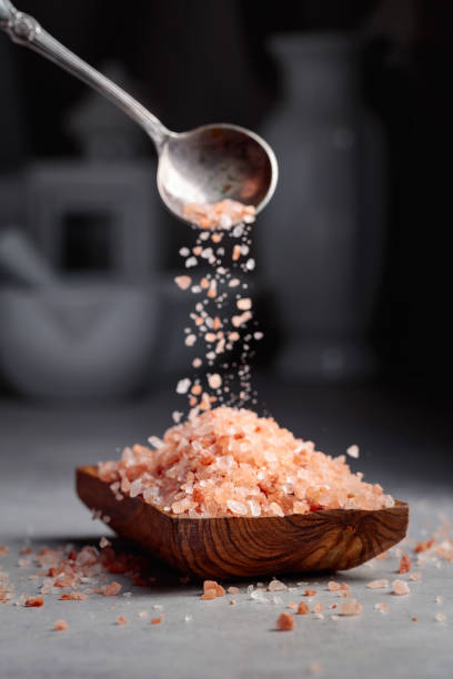 istock Pink salt is poured into a small wooden bowl. 1395867265