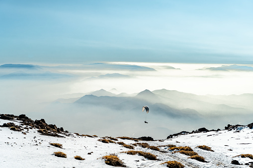 Colorida toma horizontal de persona en parapente en la montaña nevada Provincia con montañas y niebla al fondo, Chile photo