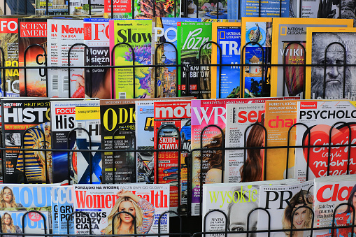 Woman relaxing at home reading a magazine while lying down on the sofa - lifestyle concepts \n**DESIGN ON MAGAZINE WAS MADE FROM SCRATCH BY US**