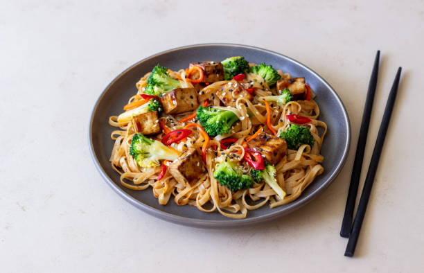 macarrão udon com tofu, brócolis, cenoura, pimenta e gergelim. alimentação saudável. comida vegetariana. comida asiática. - fried tofu tofu vegetable vegetarian food - fotografias e filmes do acervo