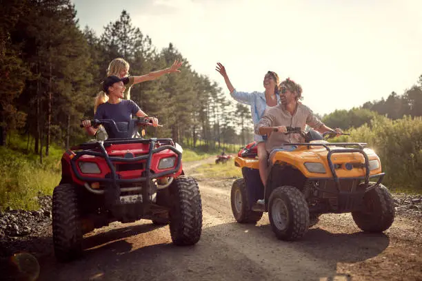 Group of traveler friends driving quads in the nature