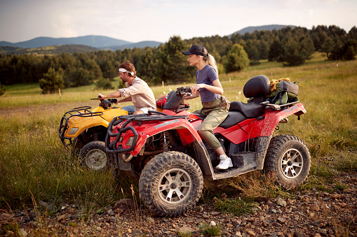 Two tourist friends driving quads together in the nature; Active vacation concept
