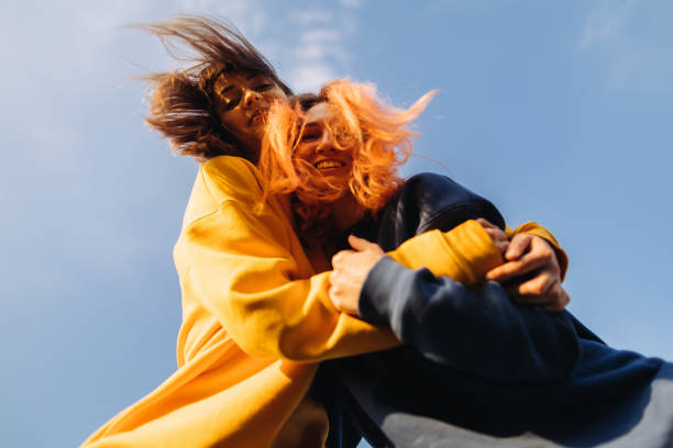 istock Two women hugging at the blue sky background at the sunset 1395875327
