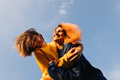 Two women hugging at the blue sky background at the sunset