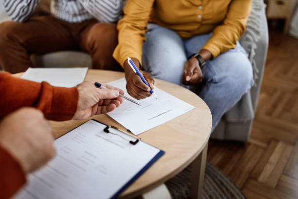 istock Counselor assisting woman in signing document at office 1395875510