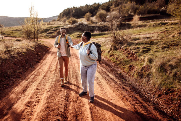 istock Male explorer holding girlfriend's hands hiking on dirt road 1395876372