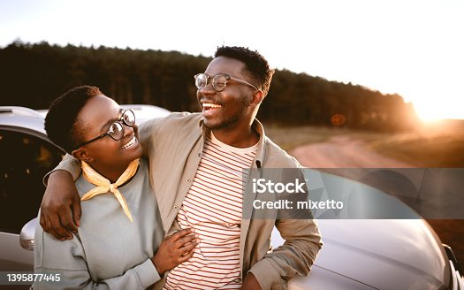 istock Man with hand on girlfriend's shoulder standing by car at sunset 1395877445