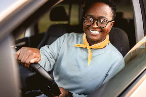 istock Smiling woman driving car seen through window 1395877533