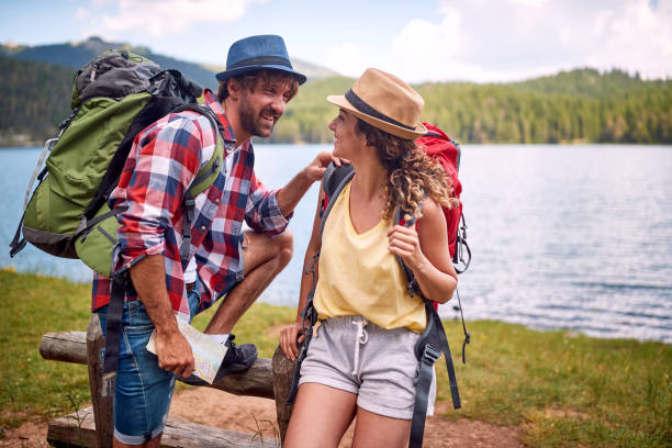 istock couple hiking by lake in nature, using map. 1395877628