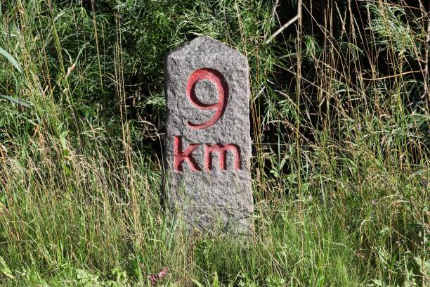 A close up shows a weathered stone milestone against a limestone wall in Mdina, Malta. Daylight reveals chiseled MILES and faint numerals, texture, and erosion.