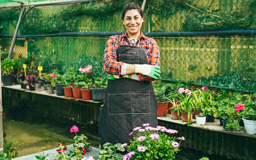 Portrait of latin woman working inside greenhouse garden - Focus on face