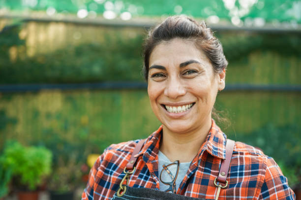 istock Latin woman smiling on camera while working inside greenhouse garden - Focus on face 1395881997