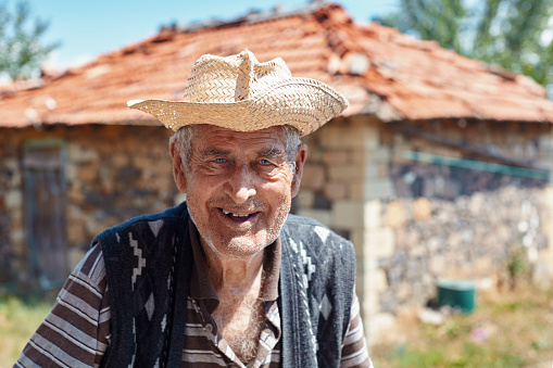 Old man with smiling happy face in front of his country house
