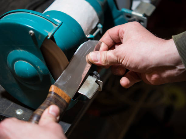 istock Knife sharpener and a hand with a blade, a man sharpens a knife on a grinder 1395883552
