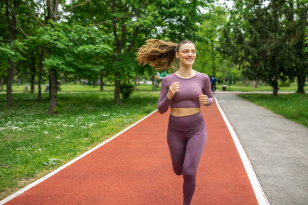 istock Smiling beautiful woman jogging in park 1395883754