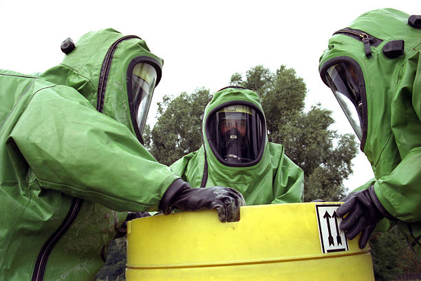 Three workers in green chemical protection suits