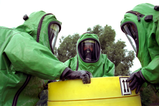 Three firemen wearing green chemical protection suits
