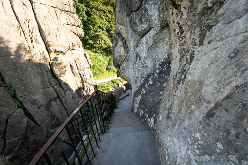 A staircase leading down to a green forest and meadow area. Photographed at Externsteine, Germany.