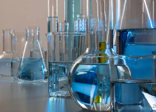 Laboratory equipment such as beaker, flask, cylinders and test tubes under a bluish light