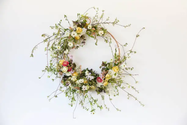 A creative and modern floral Easter wreath hanging on a white wall. Photographed in high resolution as a cut-out