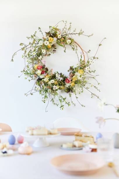 A creative and modern floral Easter wreath hanging on a white wall. Photographed in high resolution as a cut-out