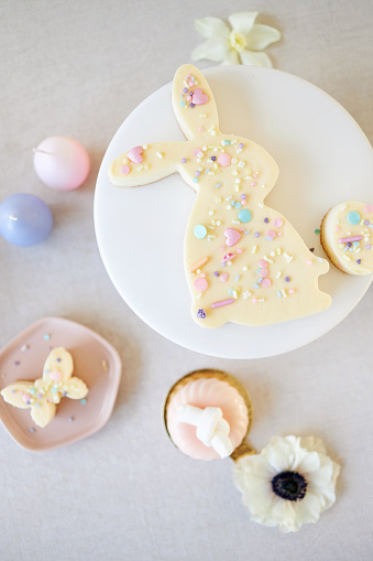 An Easter cake and small Easter cupcakes shaped like Easter bunnies, Easter chicks and Easter eggs. Served together with modern patisserie and table decoration. Photographed in high resolution