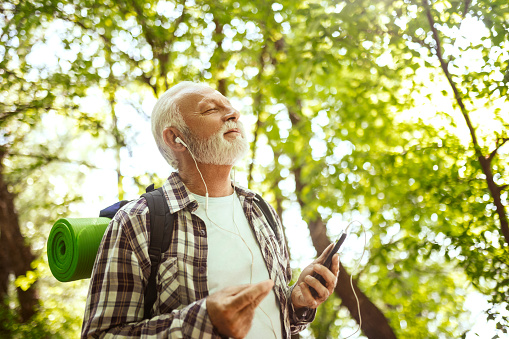 Senior man resting after hiking using smart phone