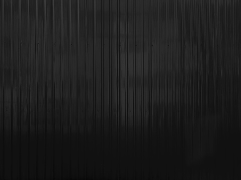 dark black metal sheet wall with corrugated pattern texture use as background. black metallic or zinc wall background for industrial concept.