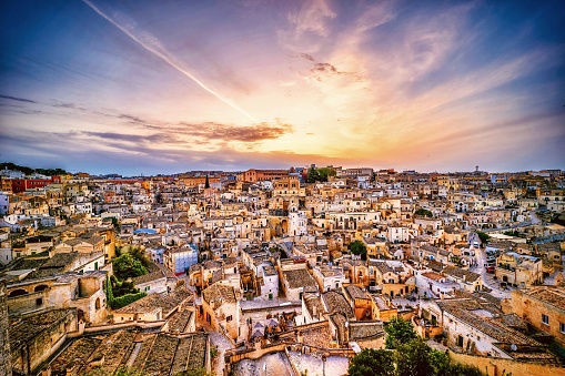 A stunning and idyllic cityscape at sunset of the old town of the Sassi of Matera, in southern Italy. The ancient city of Matera, in the southern Italian region of Basilicata, is one of the oldest urban settlements in the world, with a human presence that dates back to more than 11,000 years ago. The settlement of Matera, known as ‘Sassi’ (Stones), began with some communities that lived in the limestone caves of the area. The limestone rock itself and the cavities in the mountain have been used over the centuries for the construction of houses, streets and churches, making Matera a unique city in the world. In 1993 the Sassi of Matera were declared a World Heritage Site by Unesco. Super wide angle image in High Definition format.