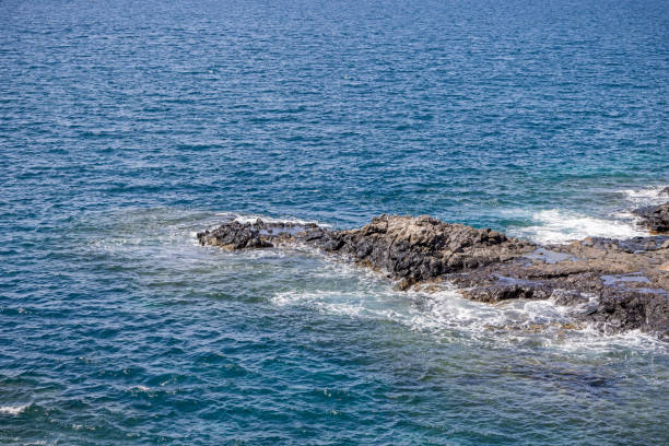 Lava rock in the Atlantic Ocean at Playa de las Americas which is a popular tourist location on the south coast of the Spanish Canary Island Tenerife.