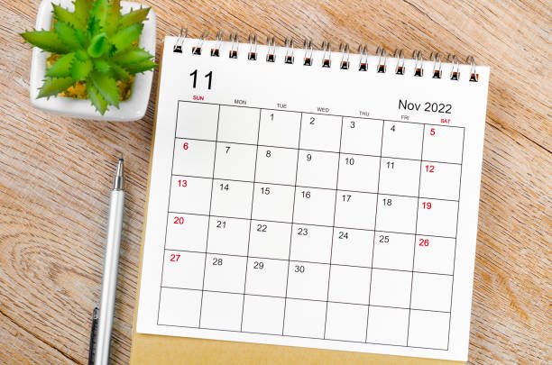 november 2022 desk calendar with pen on wooden table. - november imagens e fotografias de stock