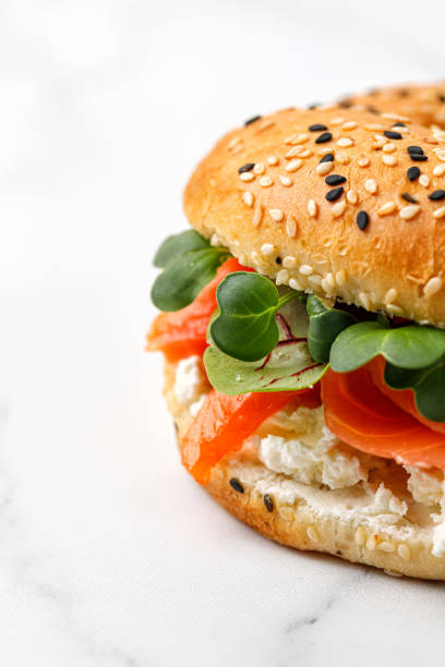 istock Bagel with salmon, cream cheese and micro greens close up on white background. 1395898167