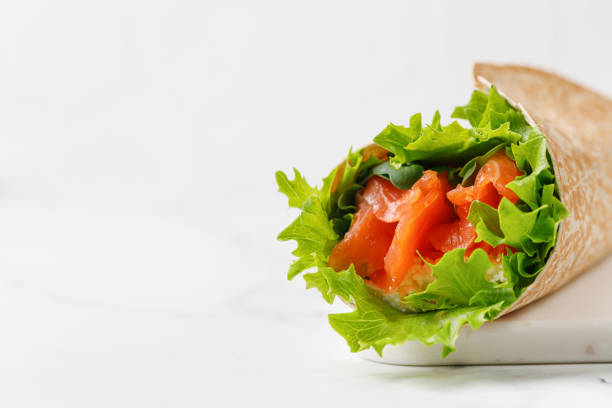 Wrap sandwich, roll with salmon and lettuce leaves. Tortilla wraps with salmon and micro greens.