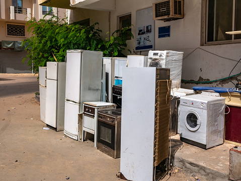 Lots of used refrigerators, gas stoves and a washing machine and outside near the repair shop.