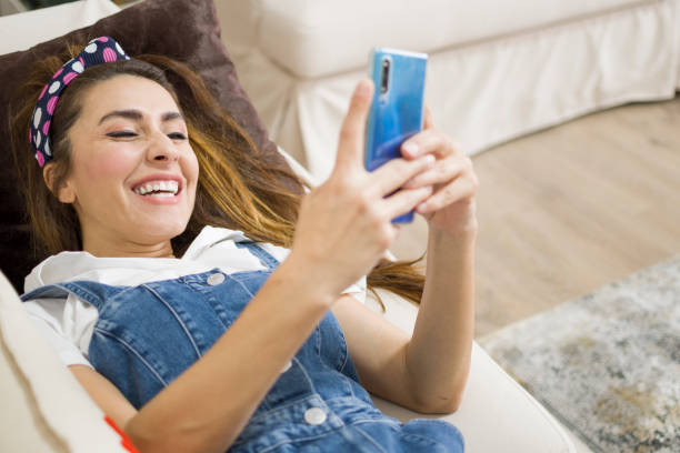 istock Beautiful woman using mobile phone on sofa 1395912054