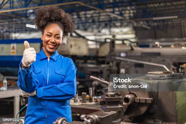 African American Young Woman Worker In Protective Uniform Operating Machine At Factory Industrialpeople Working In Industryportrait Of Female Engineer Looking Camera At Work Place Stock Photo - Download Image Now