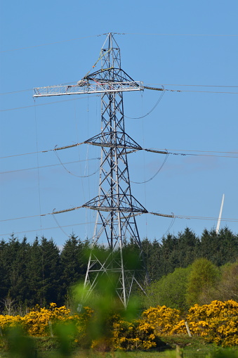 Electrical pylon undergoing electrical work against a blue sky with yellow gorse in foreground, part of system upgrade carried out in 2022 in Slaghtmanus Derry Northern Ireland