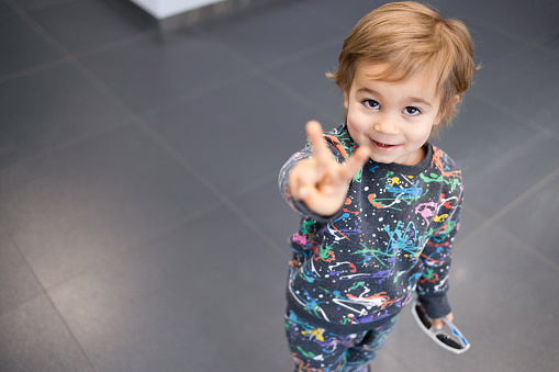 Portrait of cheerful little boy two fingers peace sign