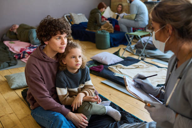 istock Young female refugee with son looking at clinician making notes in document 1395923150