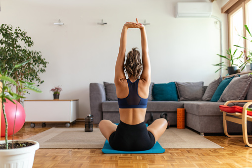 Young woman stretching and warming up for her fitness workout in living room at home