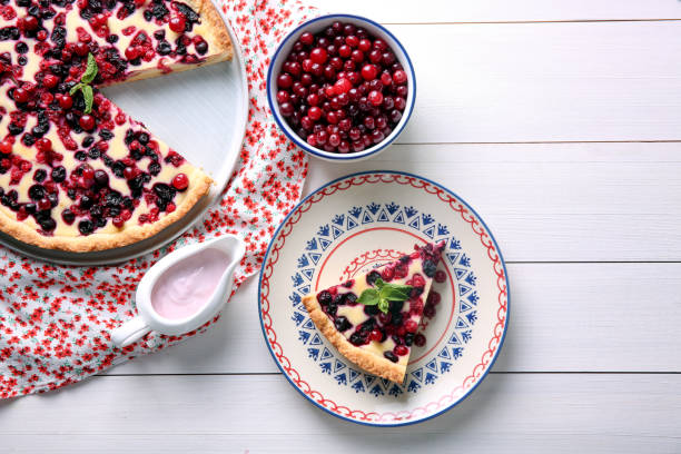 Delicious currant pie and fresh berries on white wooden table