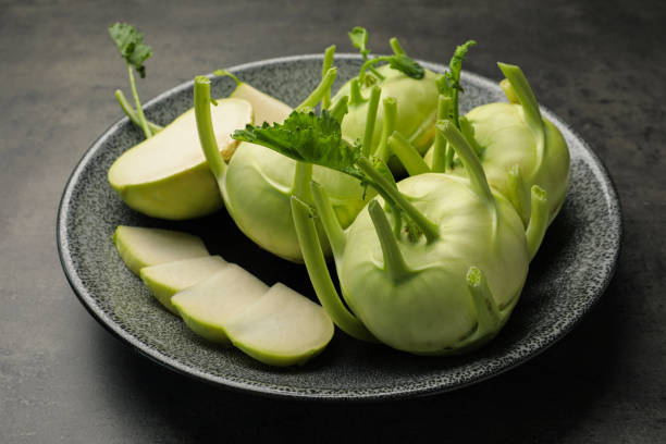 plantas de kohlrabi enteras y cortadas sobre mesa gris - kohlrabi turnip kohlrabies cabbage fotografías e imágenes de stock