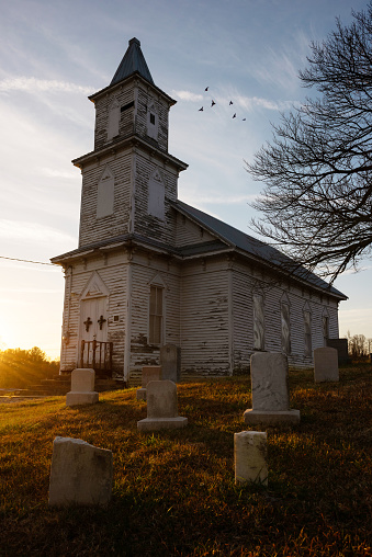 An old abandoned church on a hill with cemetery out front along the back roads of Tennessee